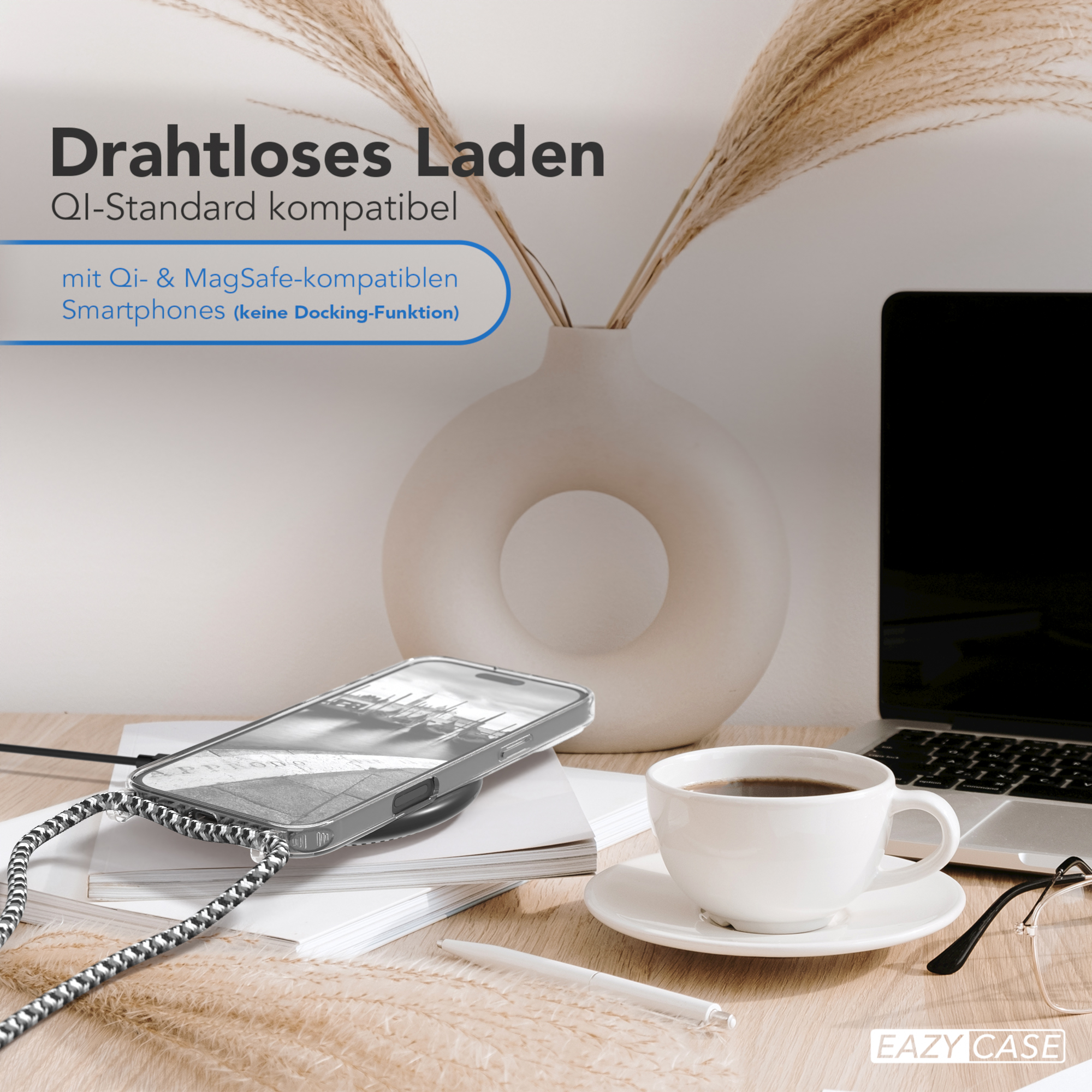 Telefon lädt kabellos. Eine Kaffeetasse, Laptop und Vase stehen auf einem Tisch.