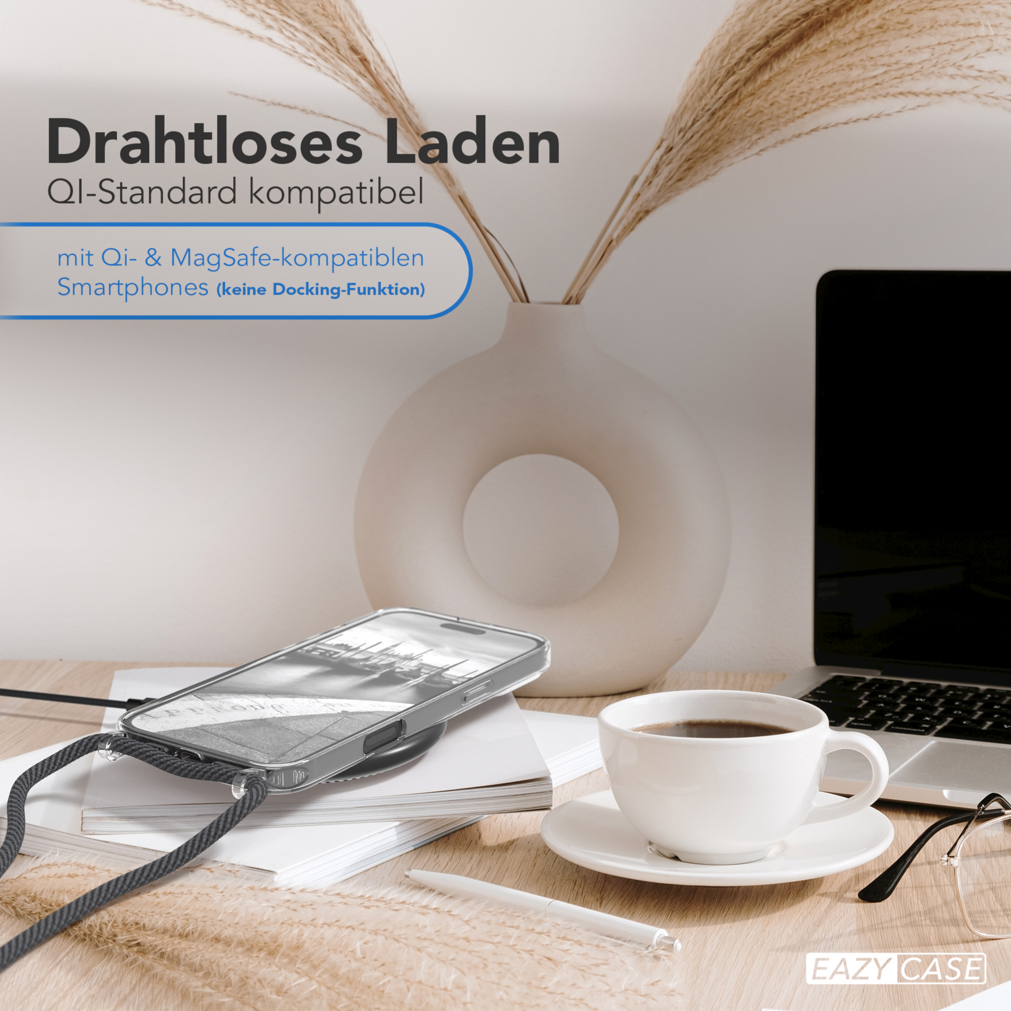 Eine transparente Handyhülle mit schwarzem Riemen auf einem Schreibtisch. Ein Laptop, Kaffee und eine Vase mit Pampasgras sind vorhanden.