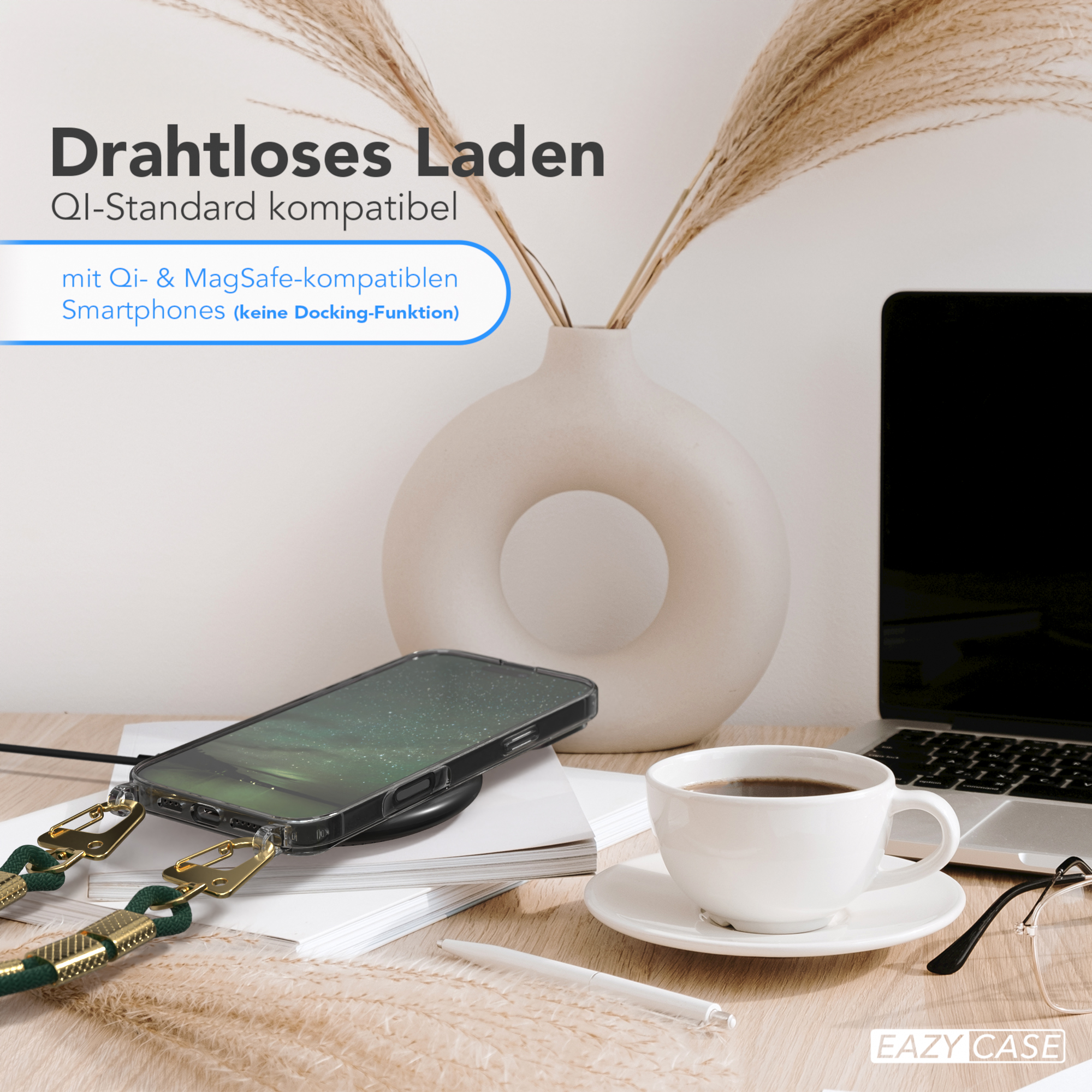 Telefon auf einem Ladegerät. Auf dem Tisch stehen eine Kaffeetasse und eine Blumenvase.
