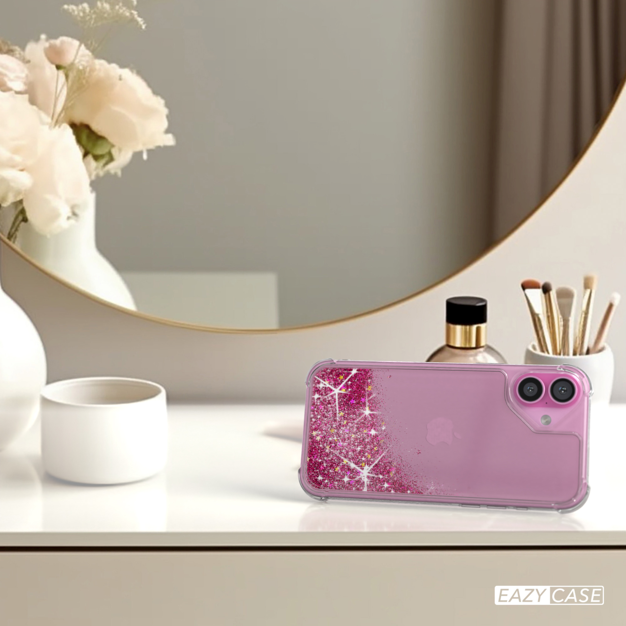 Handyhülle auf einem Tisch mit Spiegel und Kosmetika. Pinkes Glitzerdesign auf der Rückseite des Telefons.