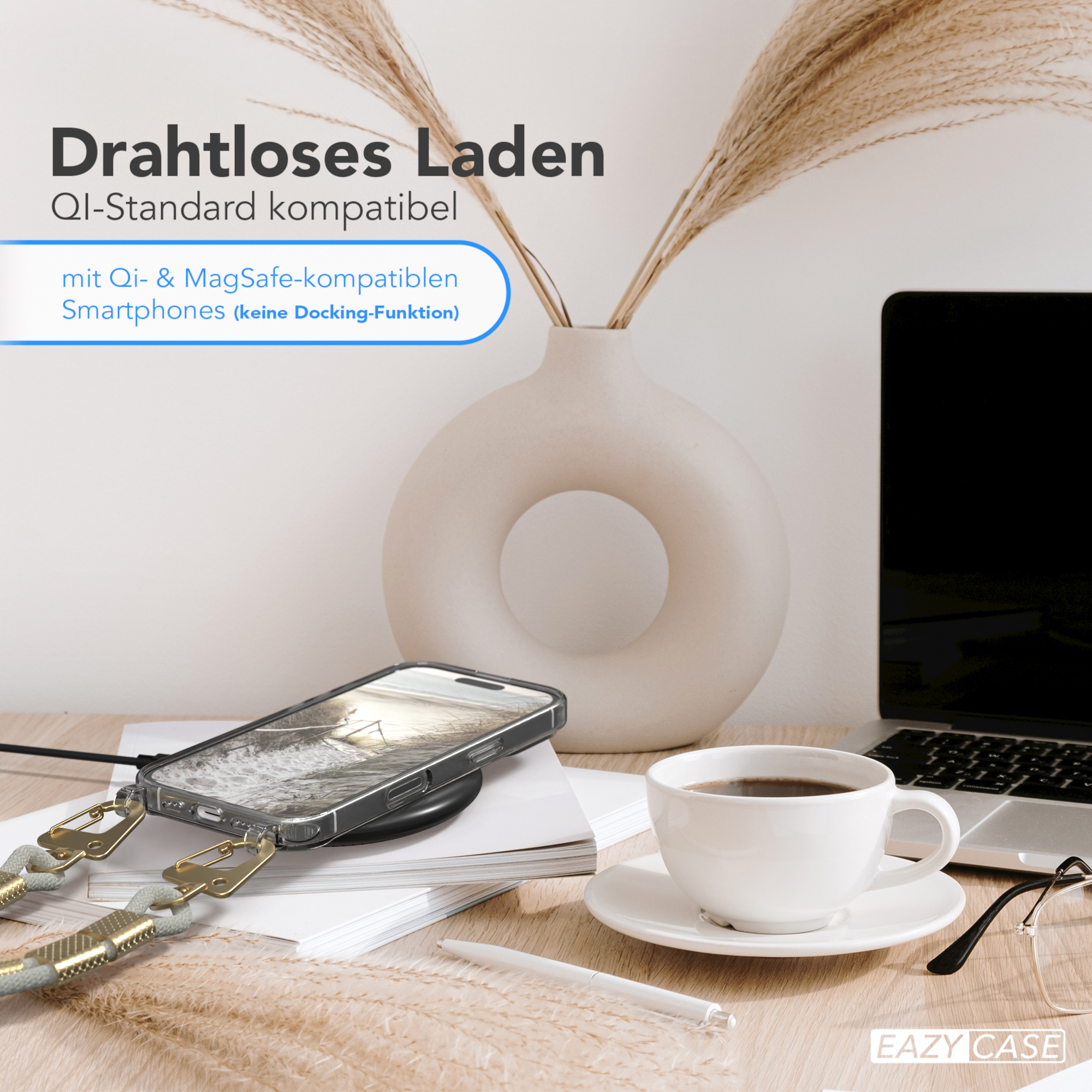 Ein Telefon auf einem Ladepad neben einer Kaffeetasse, einer Vase mit Pflanzen und einem Laptop.