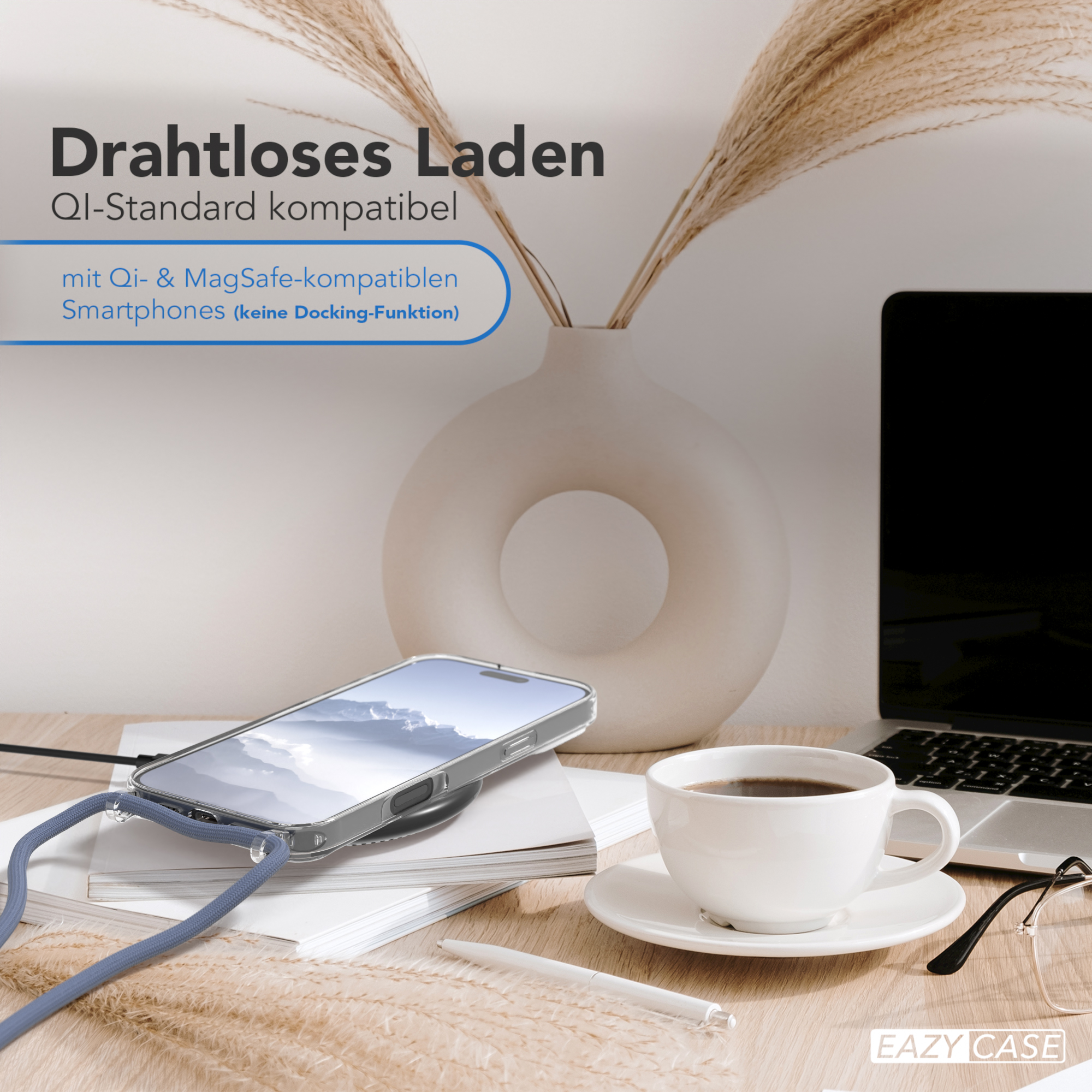 Ein Telefon auf einem Ladepad neben einer Tasse Kaffee. Eine Vase mit Schilf ist dahinter.