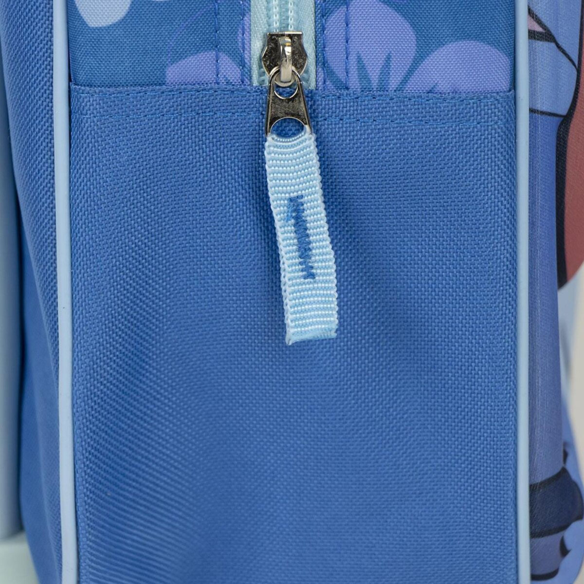 Nahaufnahme einer blauen Rucksacktasche mit Reißverschluss und hellblauem Stoffzug mit der Zahl 1.