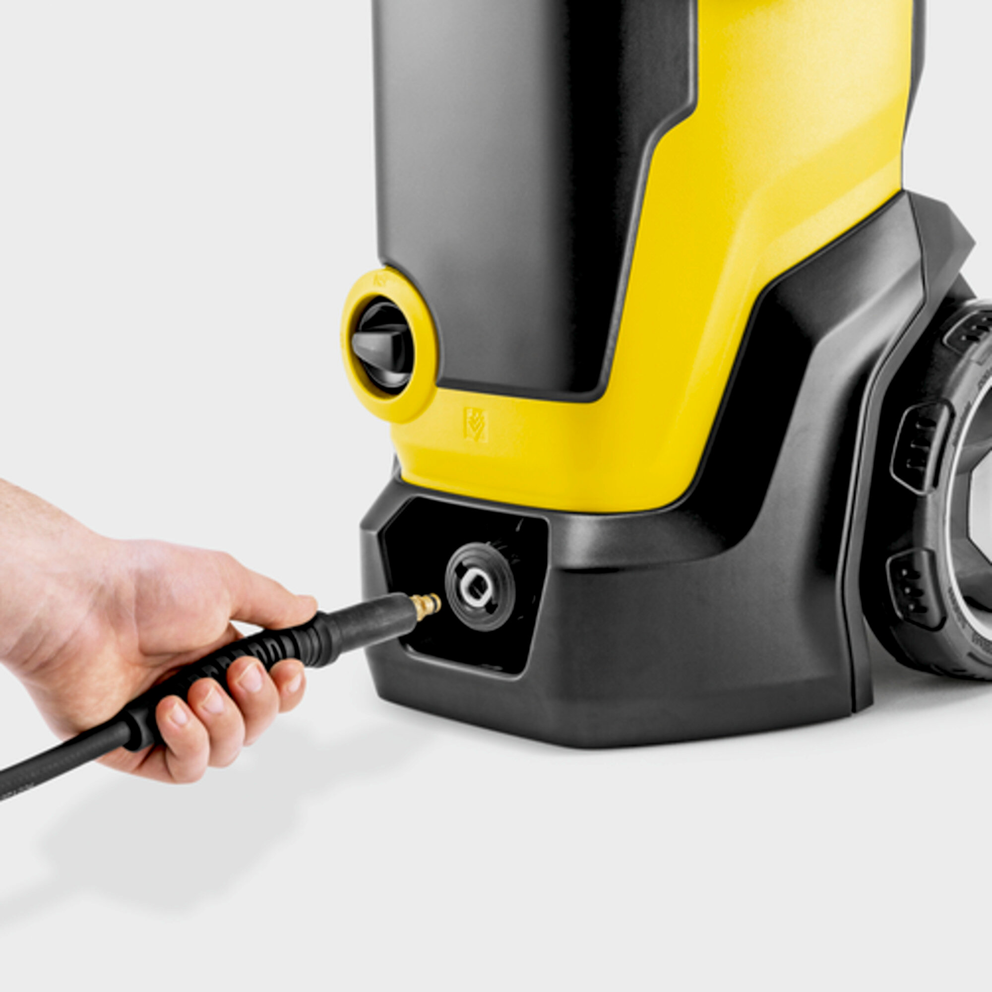 Hand hält Schlauch, der an gelb-schwarze Maschine angeschlossen wird.