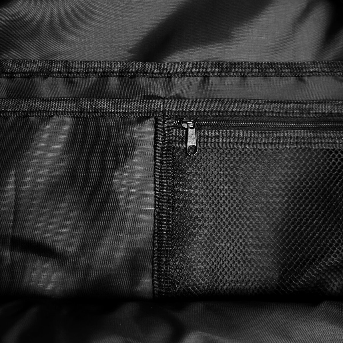 Schwarzer Tascheninnenraum mit Reißverschluss und Netztasche.