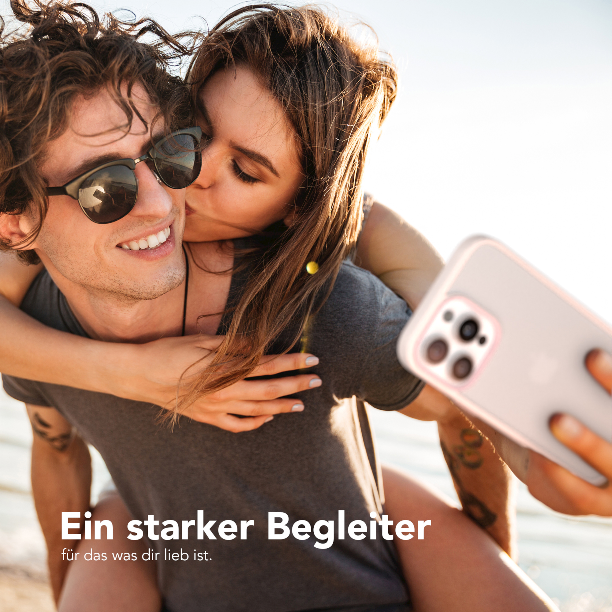 Ein Paar macht ein Selfie. Die Frau küsst den Mann, während er das Telefon hält.