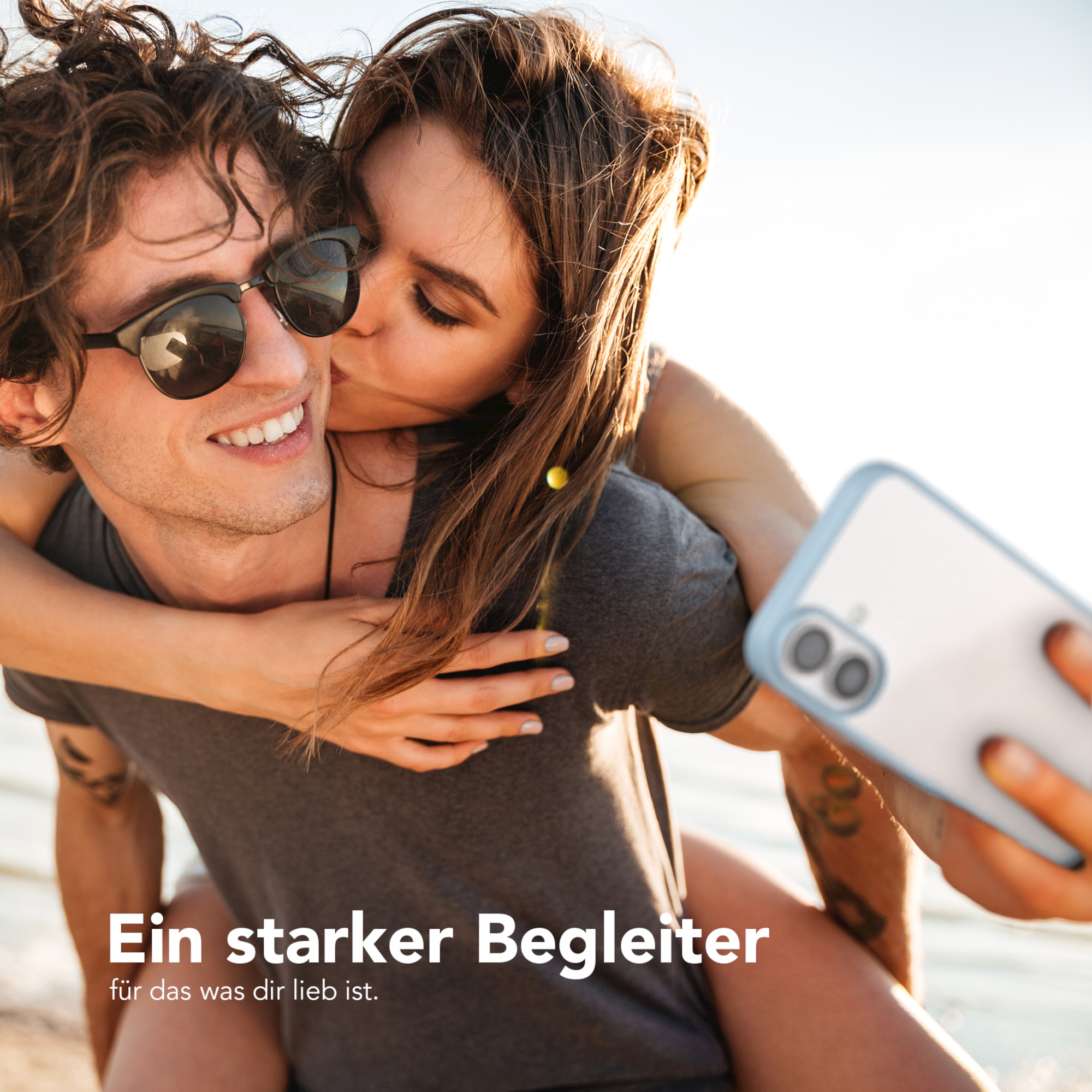 Ein Paar macht ein Selfie. Der Mann lächelt und die Frau küsst ihn.