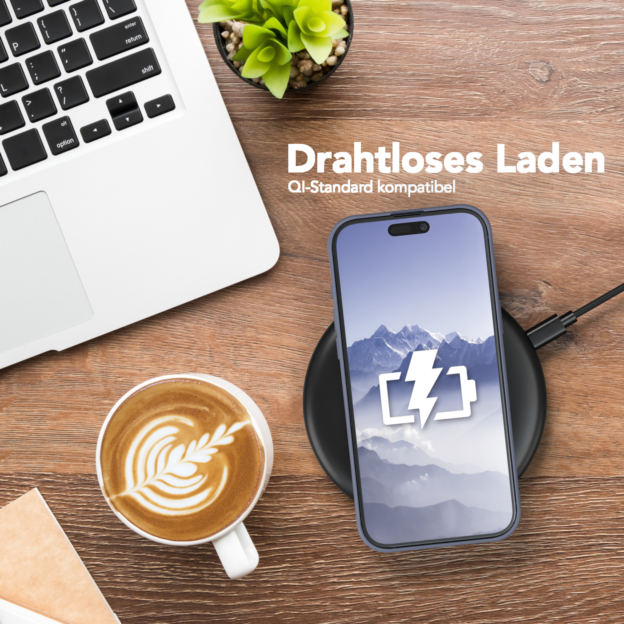 Telefon lädt auf schwarzem Pad. Laptop, Kaffee und Pflanze auf Holztisch.