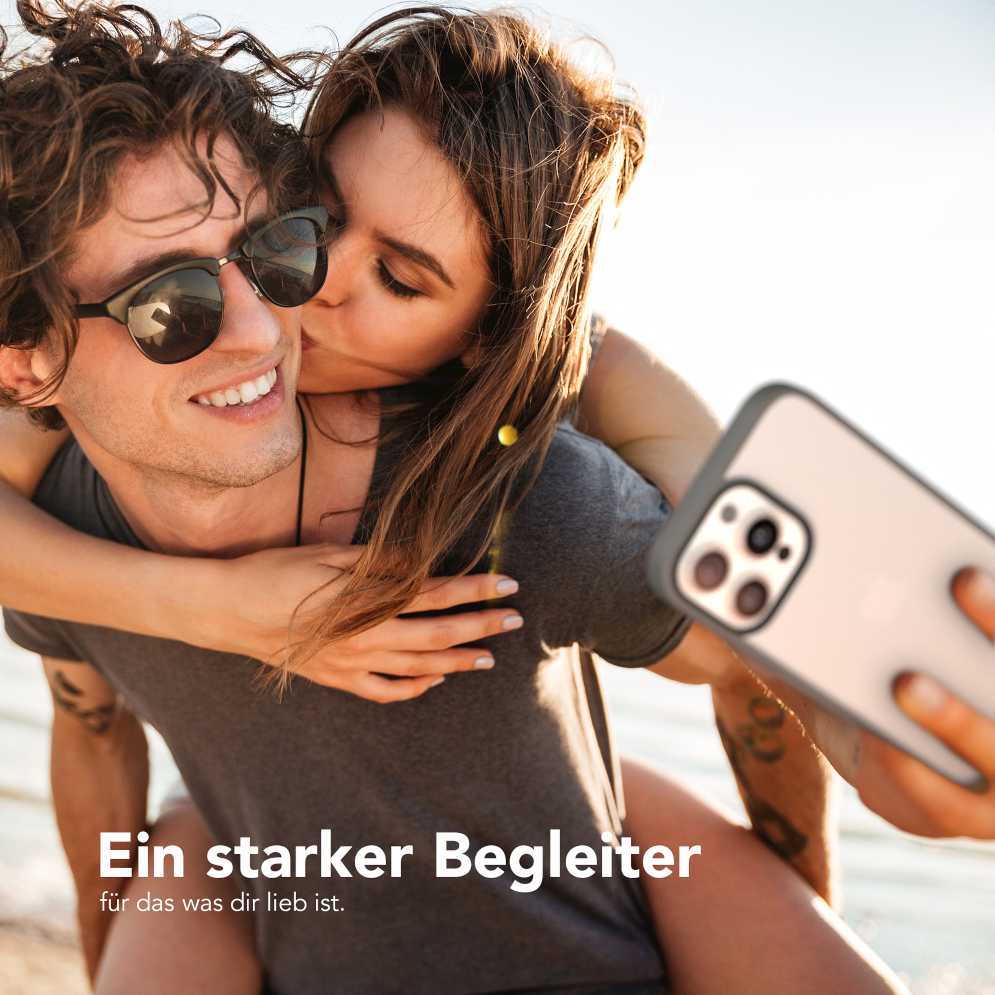 Ein Paar macht ein Selfie, die Frau küsst den Mann auf die Wange.