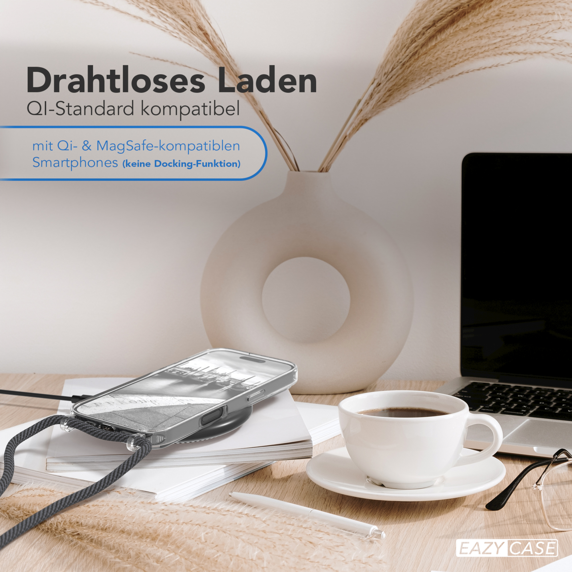 Ein Telefon auf einem Ladepad, mit einer Tasse, Brille, Laptop und einer Blumenvase.