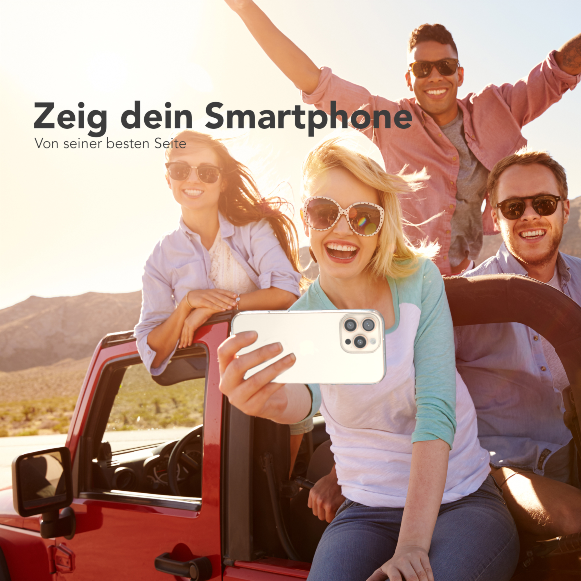 Vier Personen machen ein Selfie mit einem Telefon vor einem roten Auto.