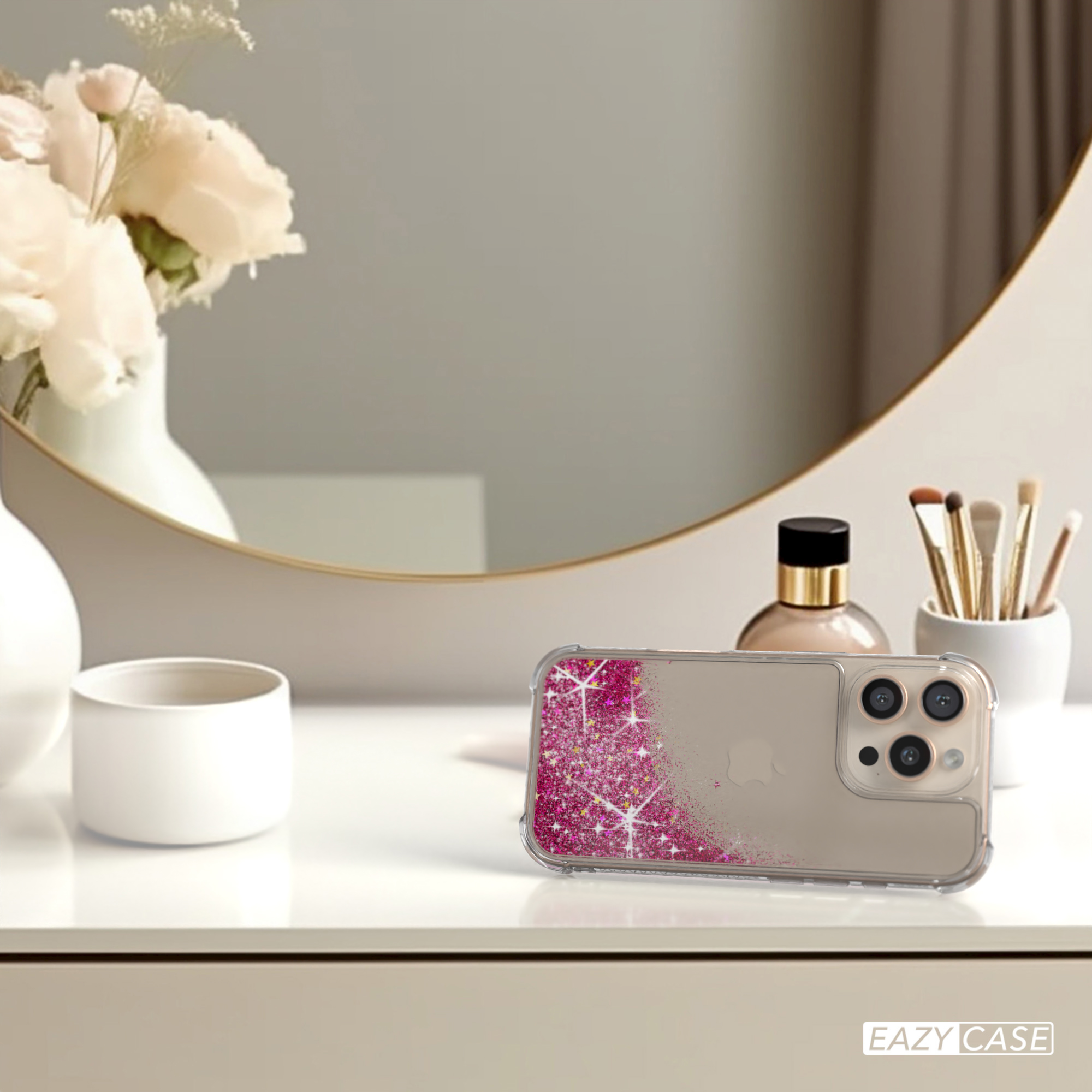 Handyhülle auf einem Tisch mit Spiegel, Blumen und Make-up. Pinkes Glitzer-Design.