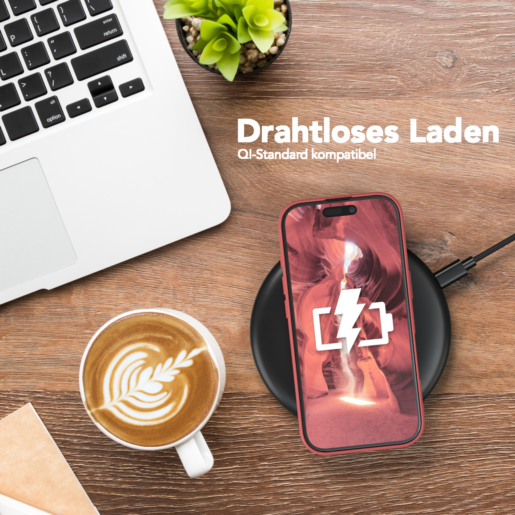 Ein Telefon lädt auf einem Pad neben einem Laptop und einer Kaffeetasse mit Latte Art.