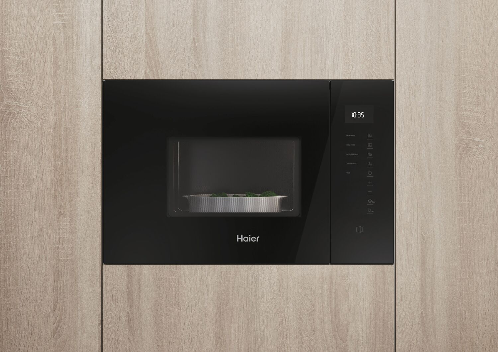 Kuchenka mikrofalowa do zabudowy. Czarna obudowa, wyświetlacz cyfrowy pokazuje 10:35. Srebrne wnętrze.
