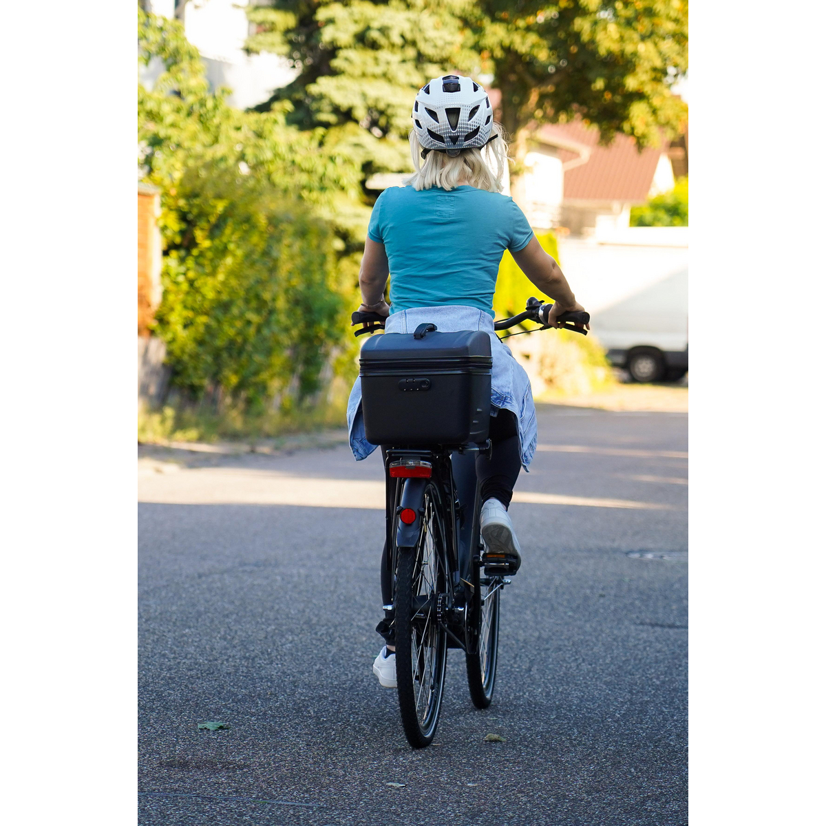 Frau fährt Fahrrad auf der Straße. Schwarze Box auf dem Fahrrad.