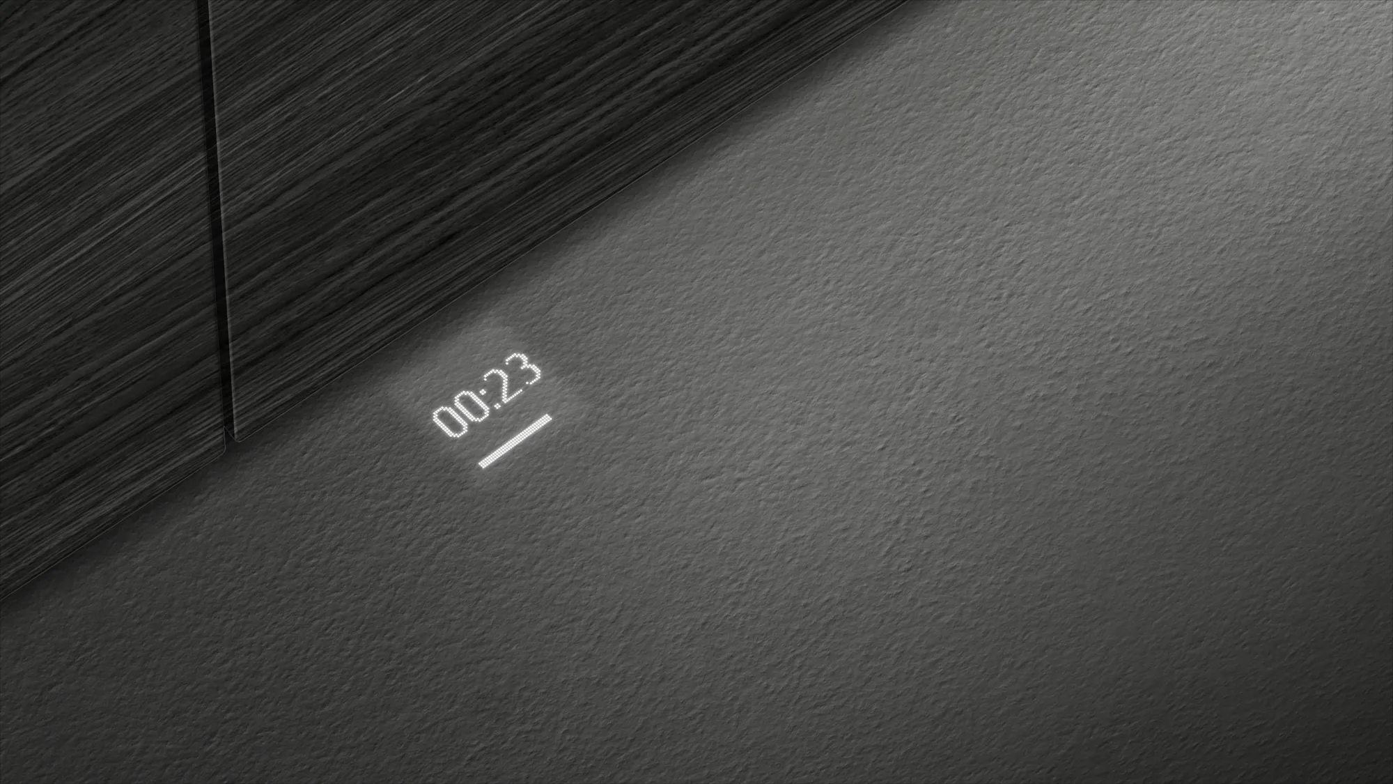 Eine Lichtprojektion an einer Wand, die die Uhrzeit 00:23 anzeigt. Grauer Hintergrund.