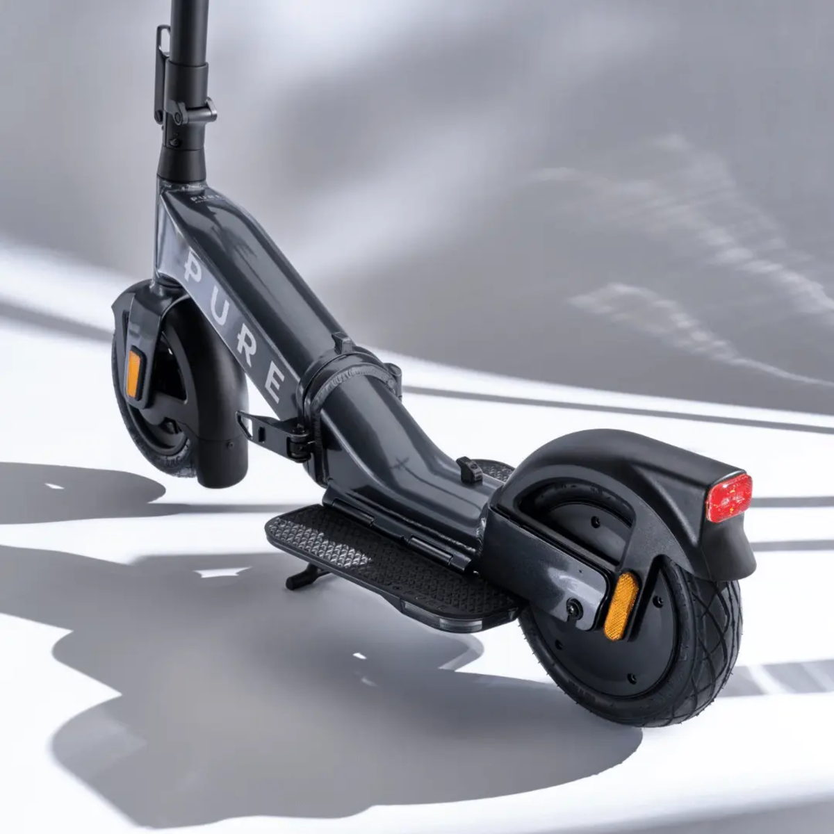 Grauer Elektroroller auf Weiß. Der Roller ist zusammengeklappt. Schatten werden auf weißen Hintergrund geworfen.