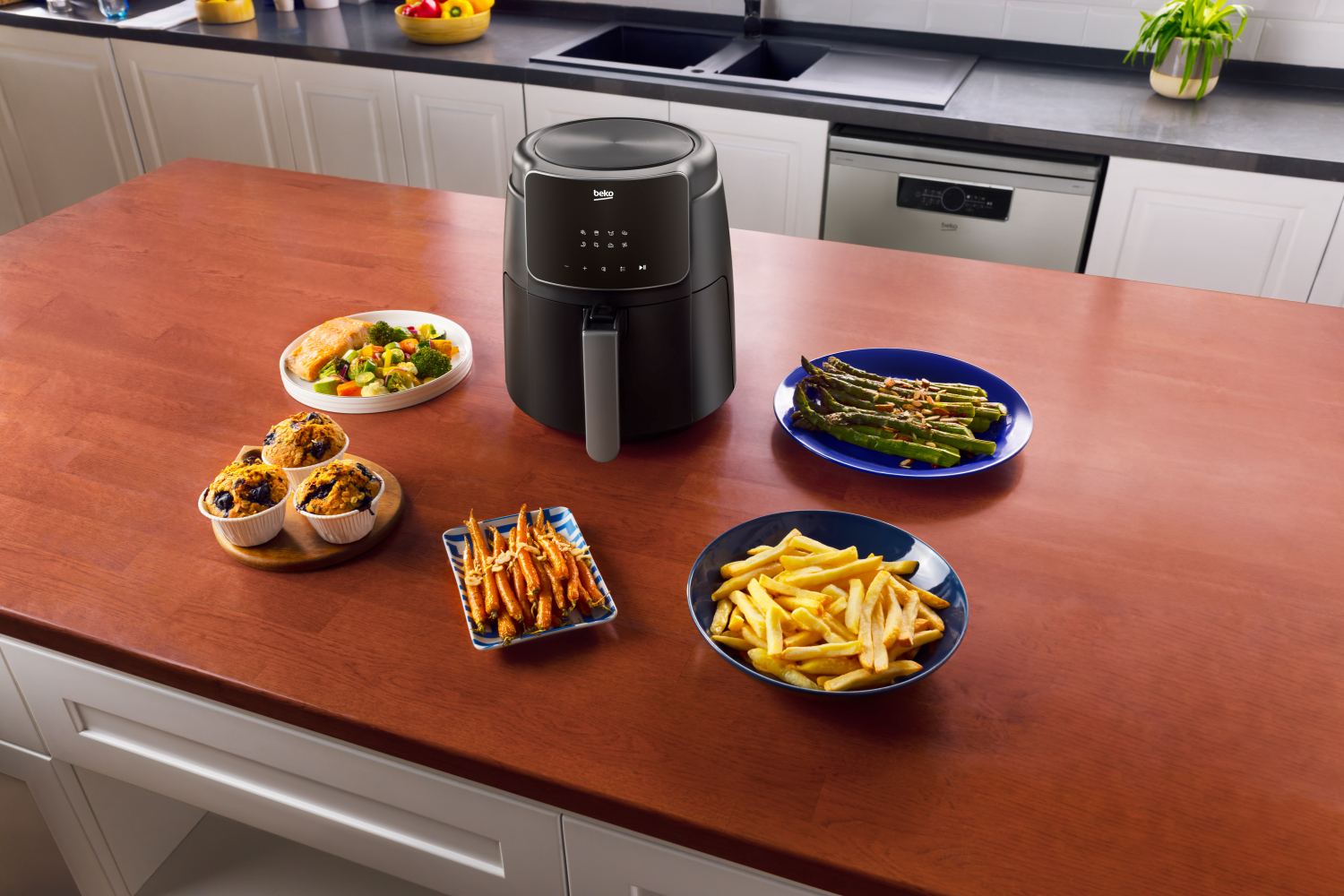 Frytownica powietrzna z różnymi potrawami na drewnianym stole w kuchni.