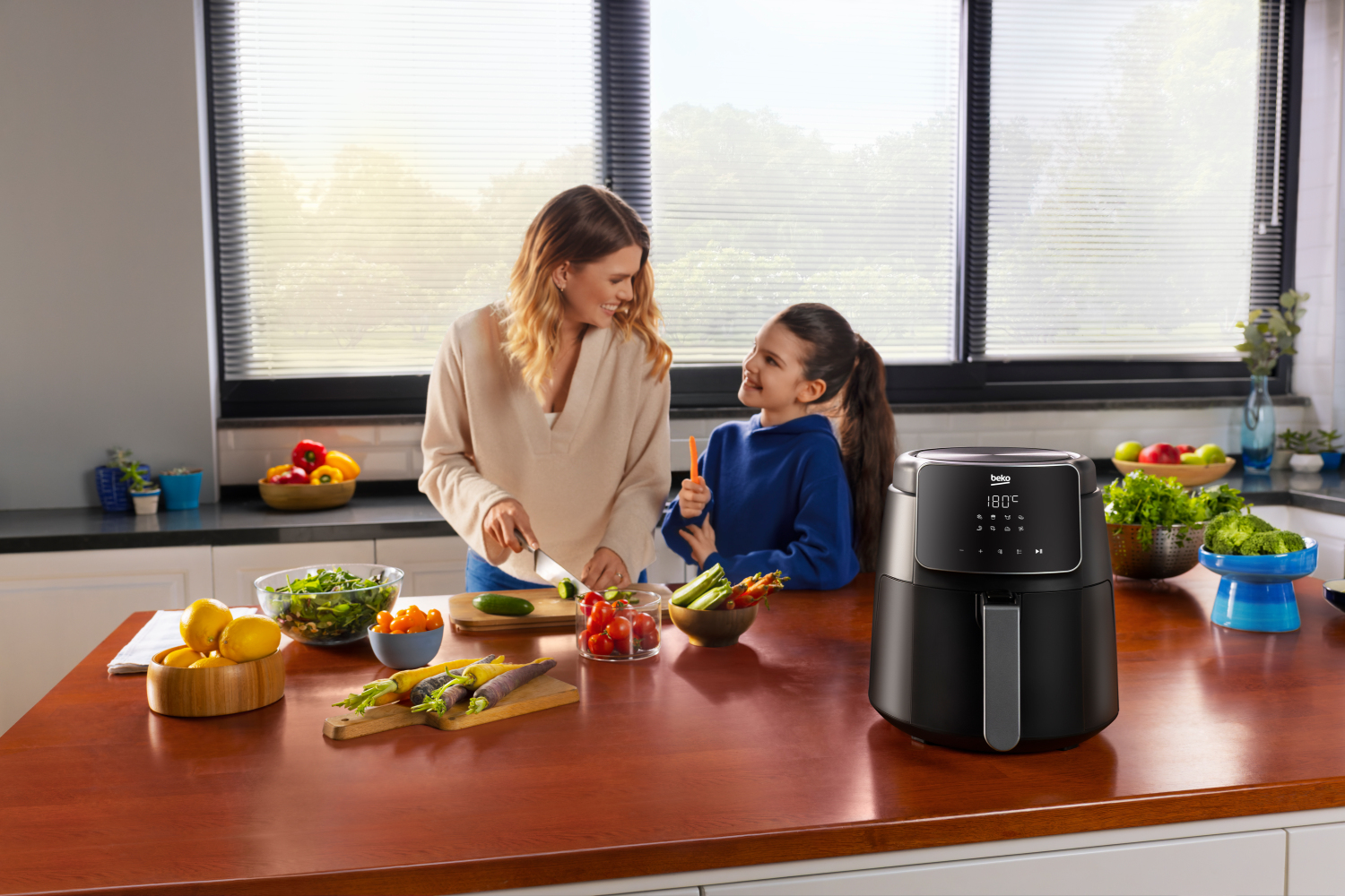 Kobieta i dziecko w kuchni przygotowują posiłek, z frytkownicą na blacie.