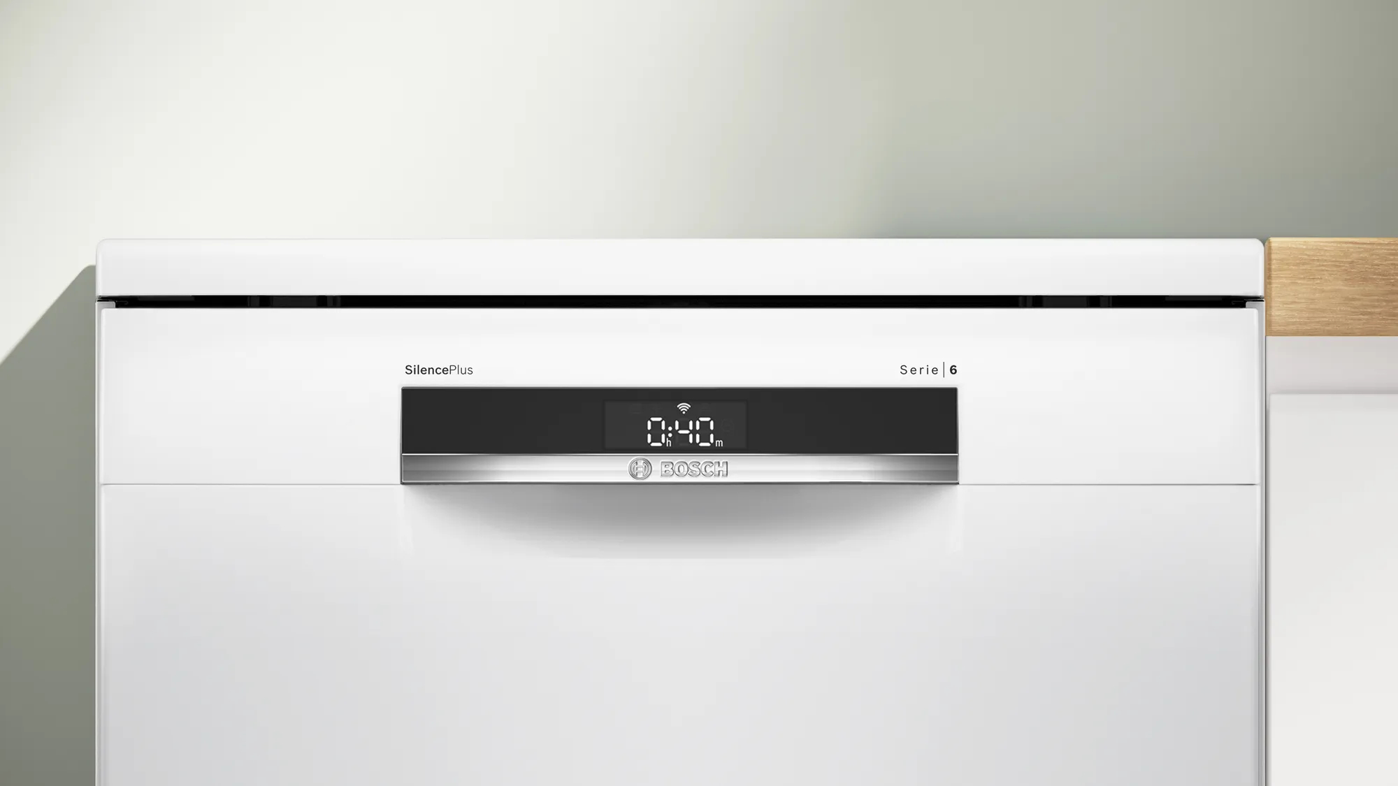 Un lavavajillas blanco con una pantalla que muestra la hora. Pared blanca lisa en el fondo.