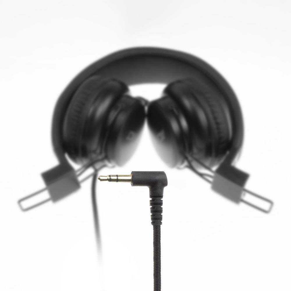 Casque noir, en arrière-plan. La prise est mise au point, sur fond blanc.