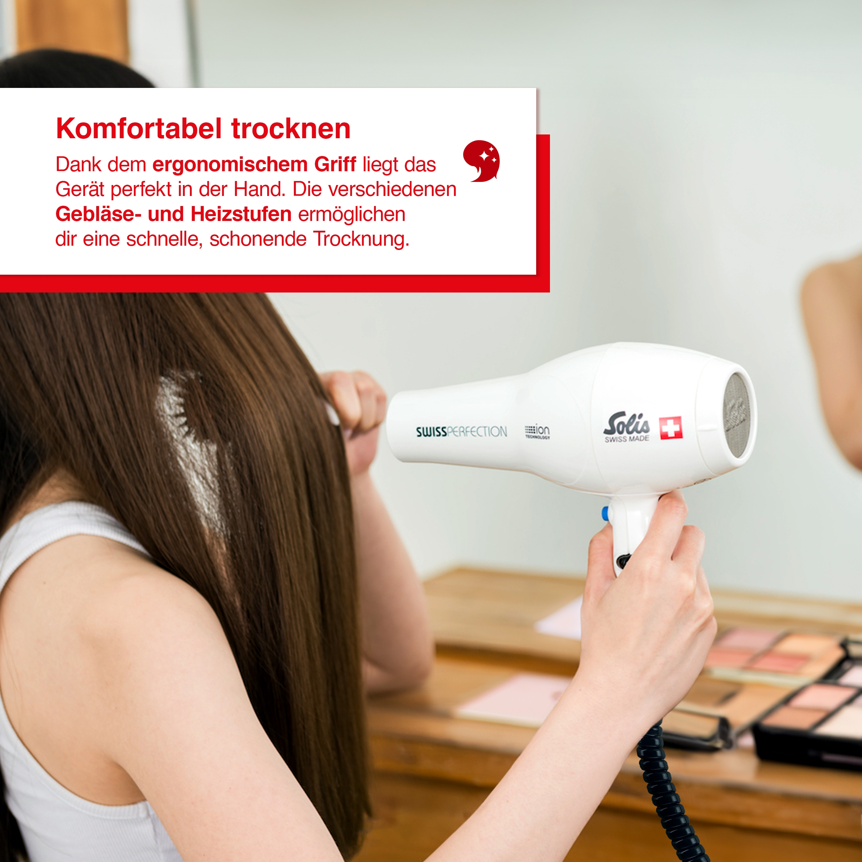 Eine Frau trocknet ihre Haare mit einem weißen Haartrockner. Der Text lautet 'Komfortabel trocknen' und 'Swiss Perfection'.