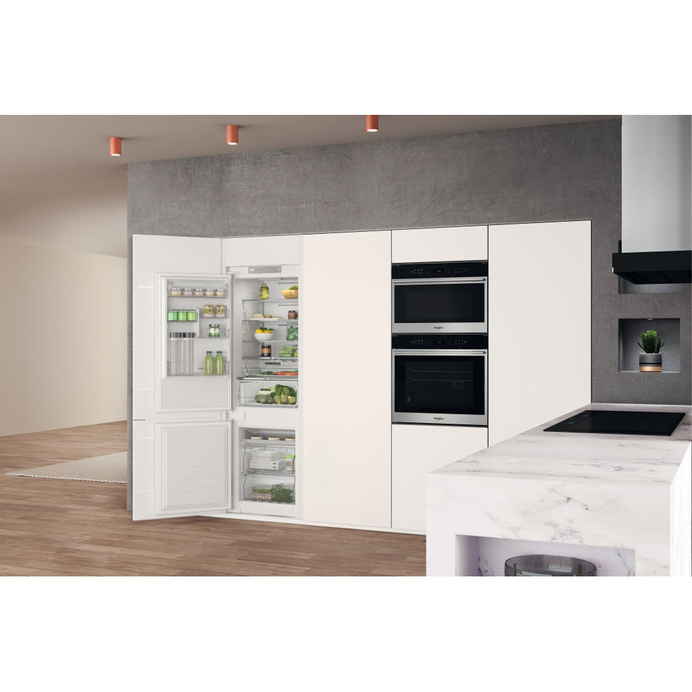 Cocina moderna con frigorífico empotrado, hornos y encimera de mármol.
