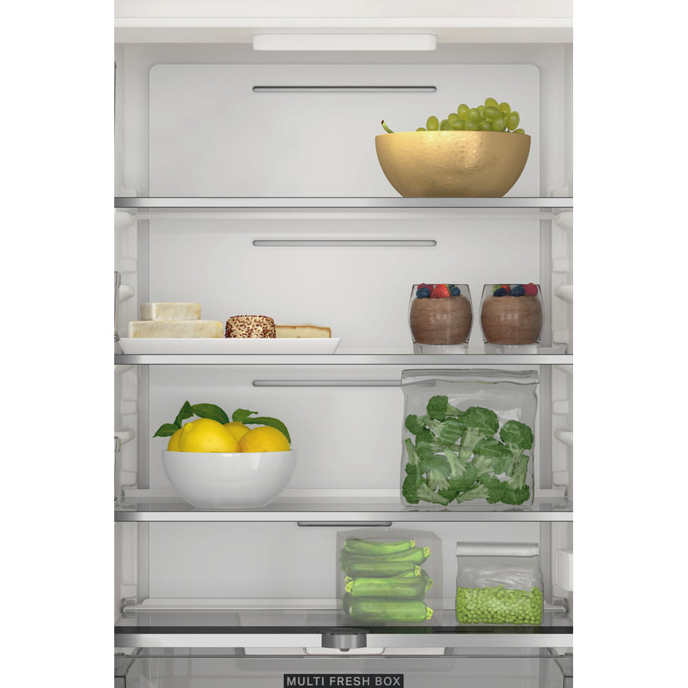 Interior de nevera con estantes que contienen frutas, queso y alimentos envasados.
