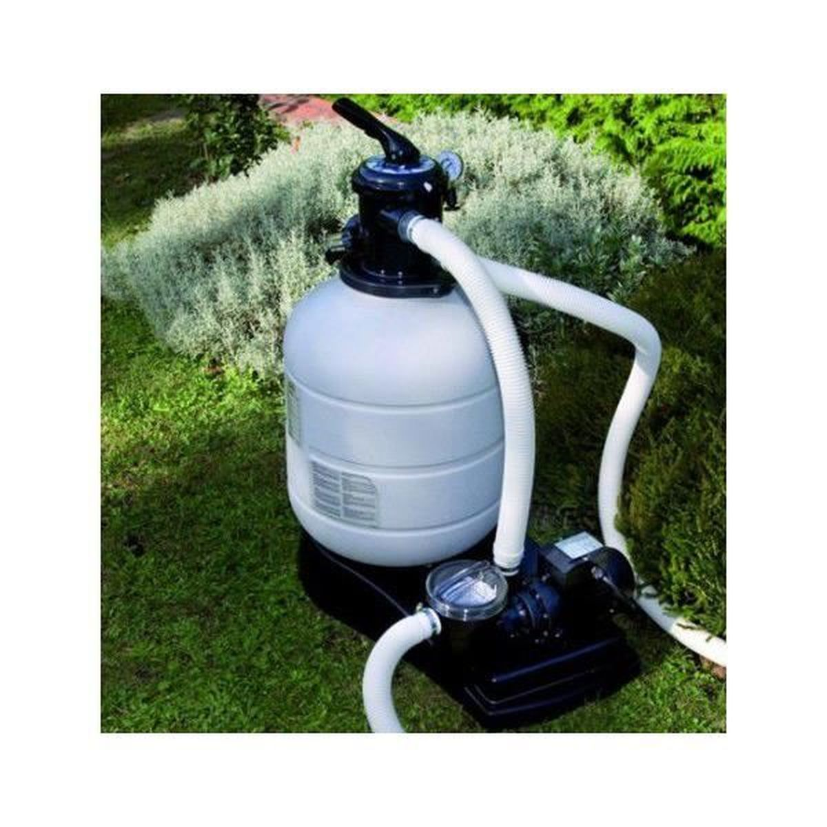 Ein weiß-schwarzes Poolfiltersystem auf grünem Gras mit einer Hecke im Hintergrund.
