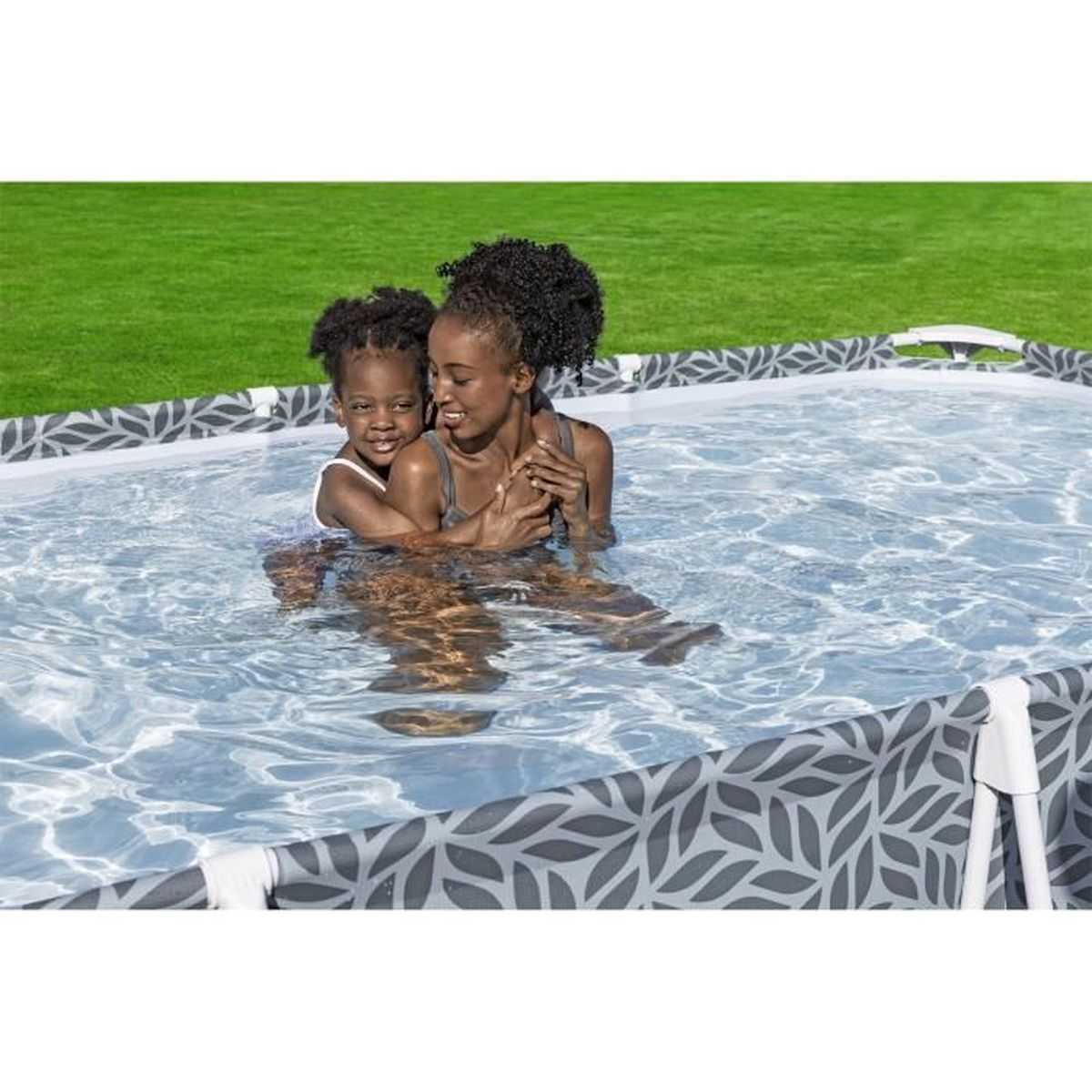 Mère et enfant dans une piscine. La piscine a un motif de feuilles et un cadre gris. Elles s'embrassent.