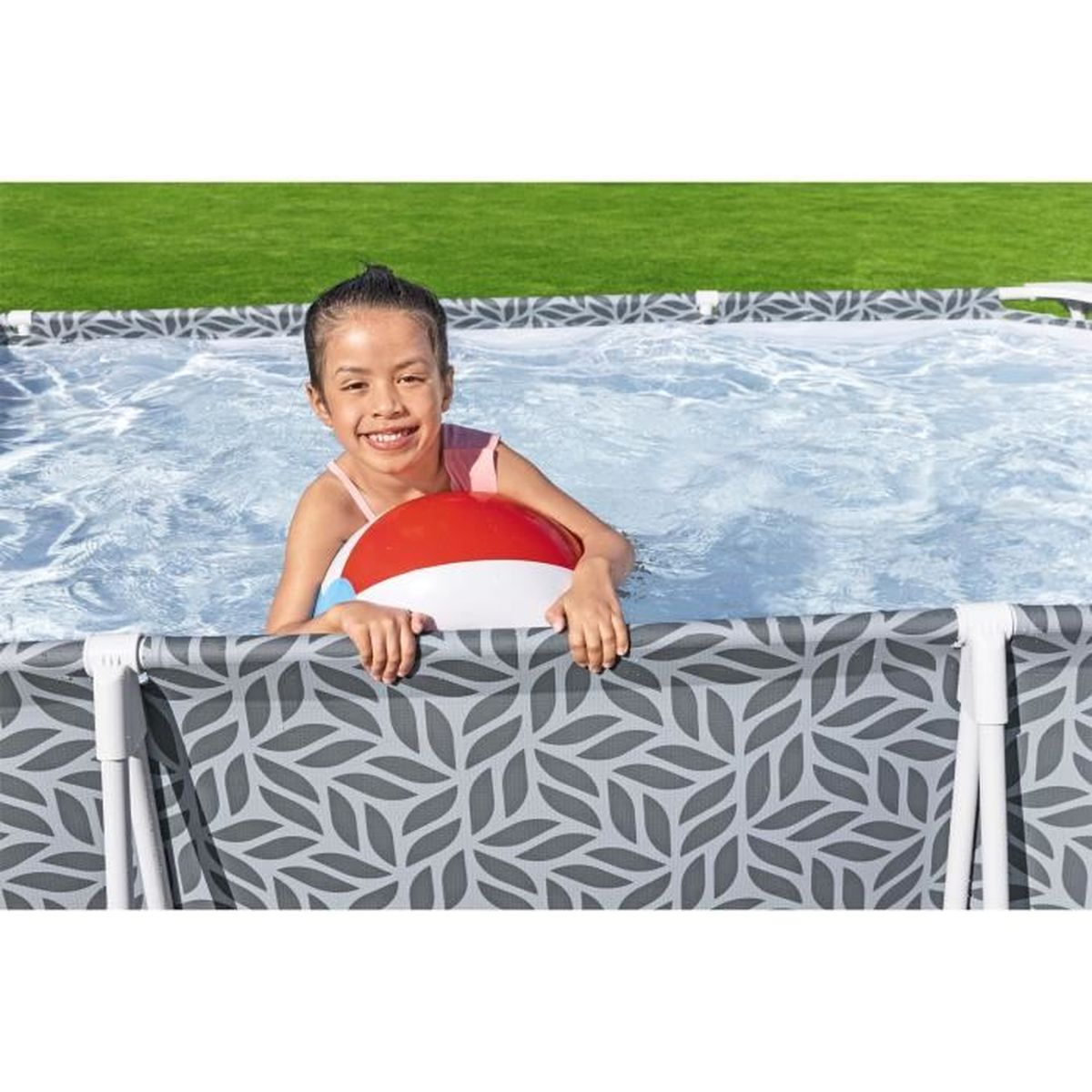 Une fille en maillot de bain rose tenant un ballon de plage rouge, blanc et bleu dans une piscine.