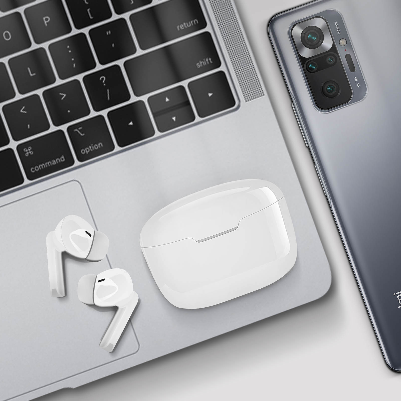 Een laptop met een telefoon en een witte oplaadcase met oordopjes erop.