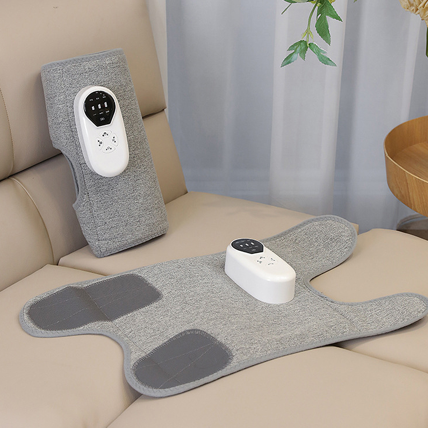Almohadillas térmicas médicas grises con controladores blancos en un sofá beige.