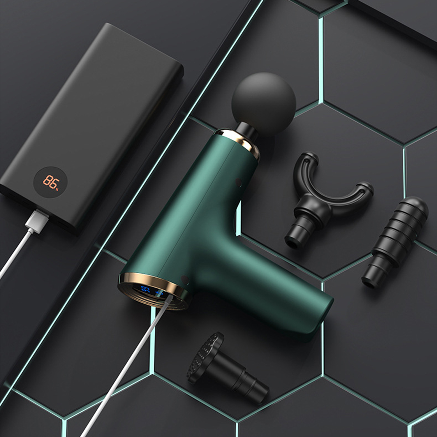 Pistola de masaje verde con accesorios sobre una superficie negra y azul. También hay un banco de energía y un cable.