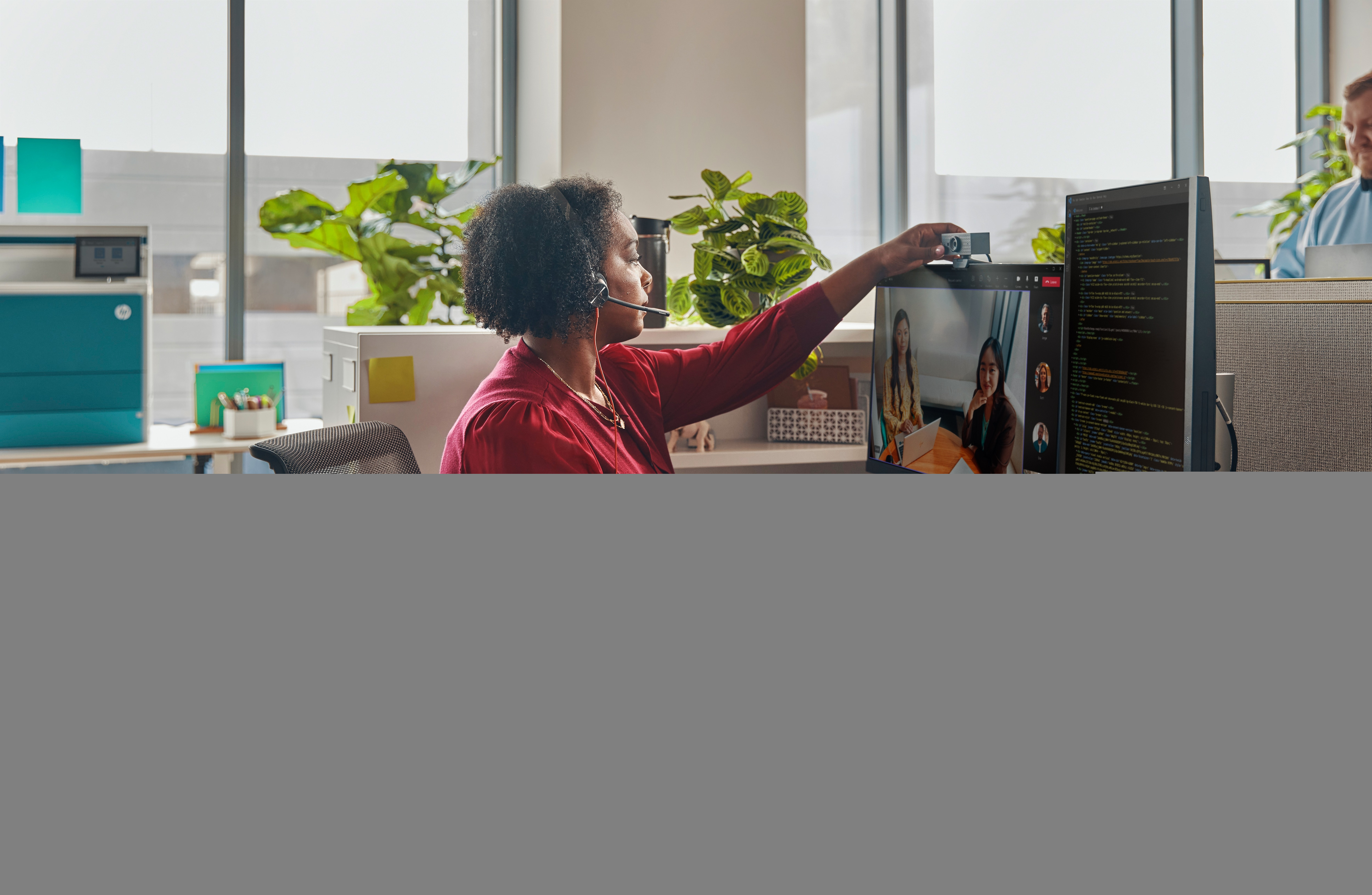 Kobieta w czerwonej koszuli ustawia kamerę internetową na ekranie komputera.