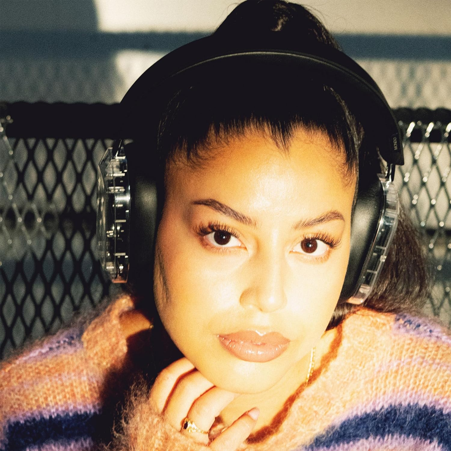 Młoda kobieta w czarnych słuchawkach. Patrzy w kamerę. Tło jest rozmyte.