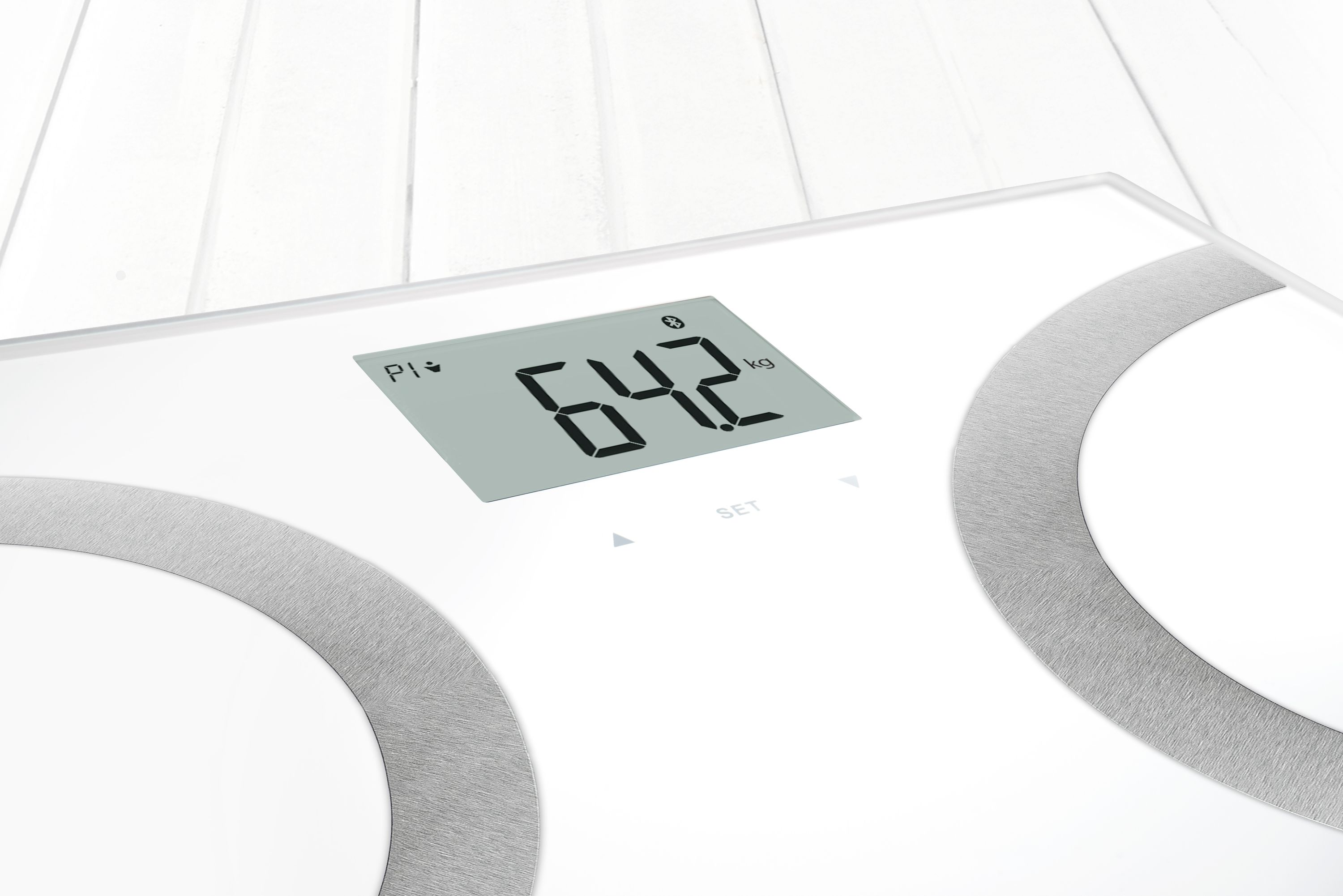 Digitale weegschaal met 64,2 kg. Wit oppervlak met zilveren cirkels.