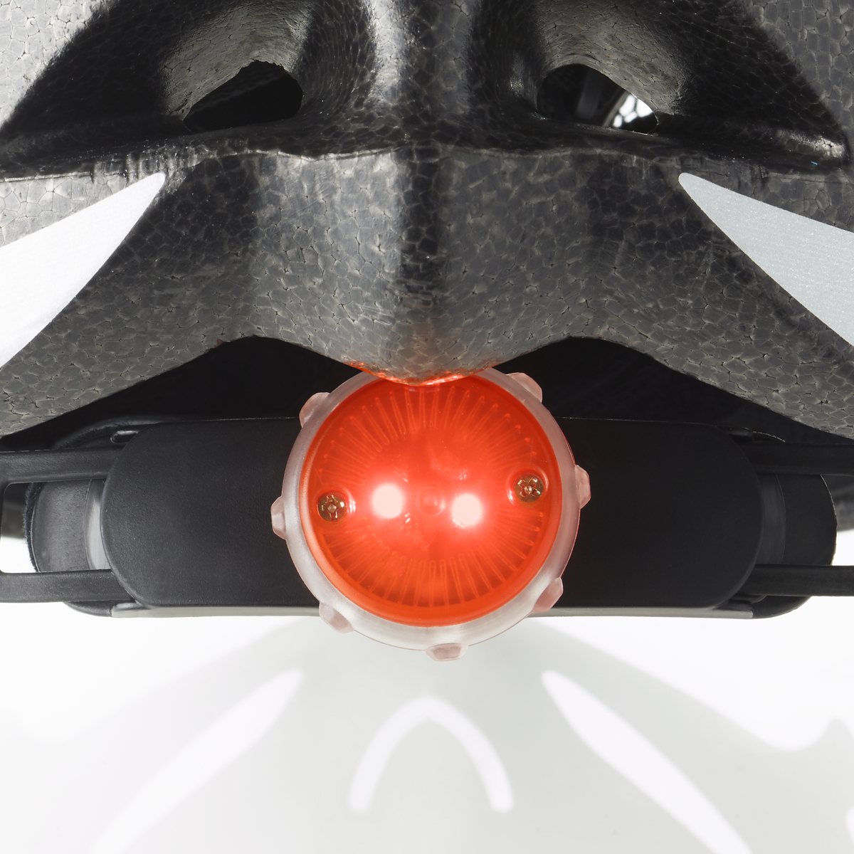 Nahaufnahme eines schwarzen Helms mit rotem Rücklicht. Weißer Hintergrund.
