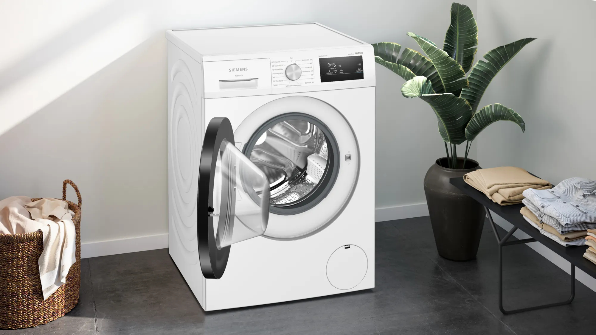 Weiße Siemens-Waschmaschine mit offener Tür. Inkl. Wäschekorb, Pflanze und Kleidung.
