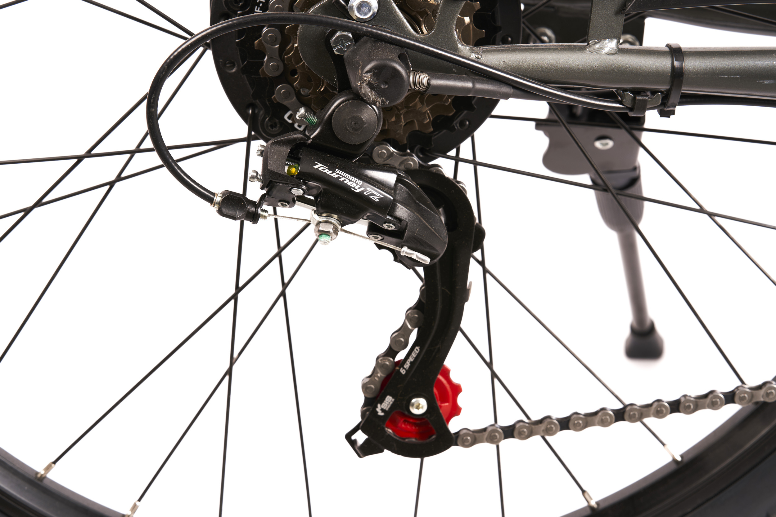 Zbliżenie mechanizmu zmiany biegów roweru z widocznym łańcuchem i przerzutką na białym tle.