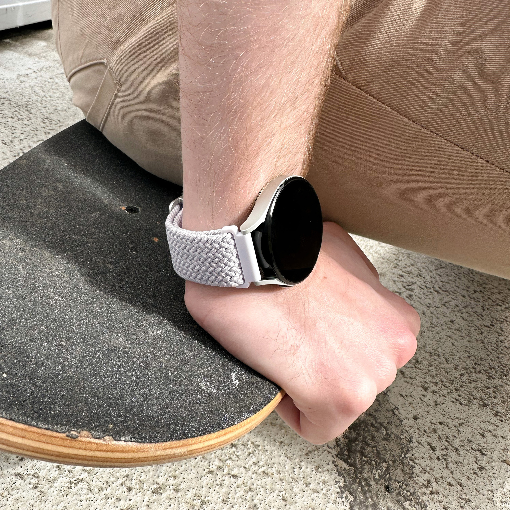 Person trägt Smartwatch auf einem Skateboard mit schwarzer Oberfläche.