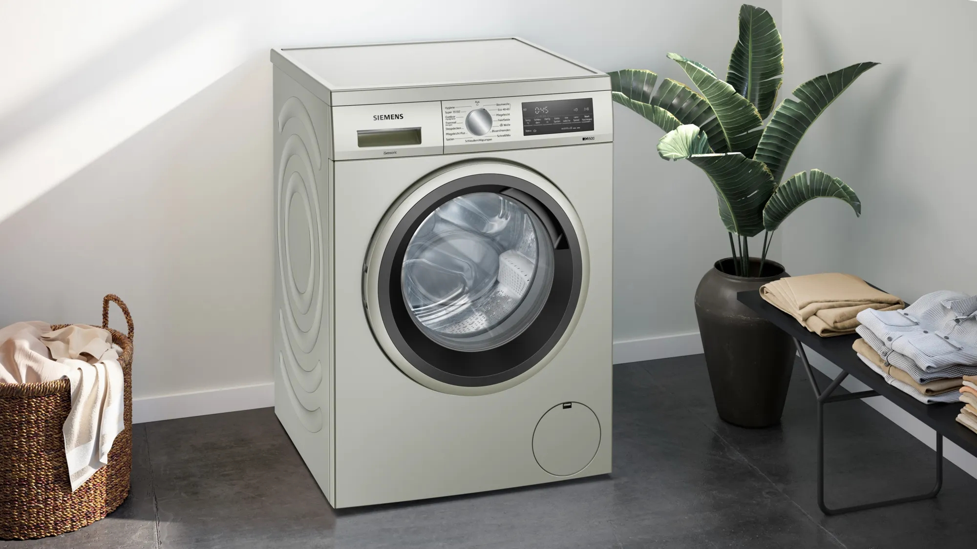 Weiße Siemens Waschmaschine neben einer Pflanze und einem Wäschekorb. Moderner Waschraum.