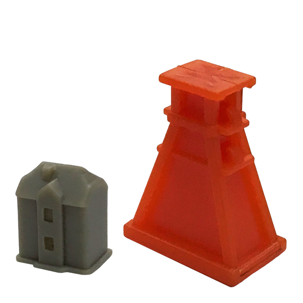 Zwei Plastikspielzeugteile: ein graues Haus und ein hoher roter Turm auf weißem Hintergrund.