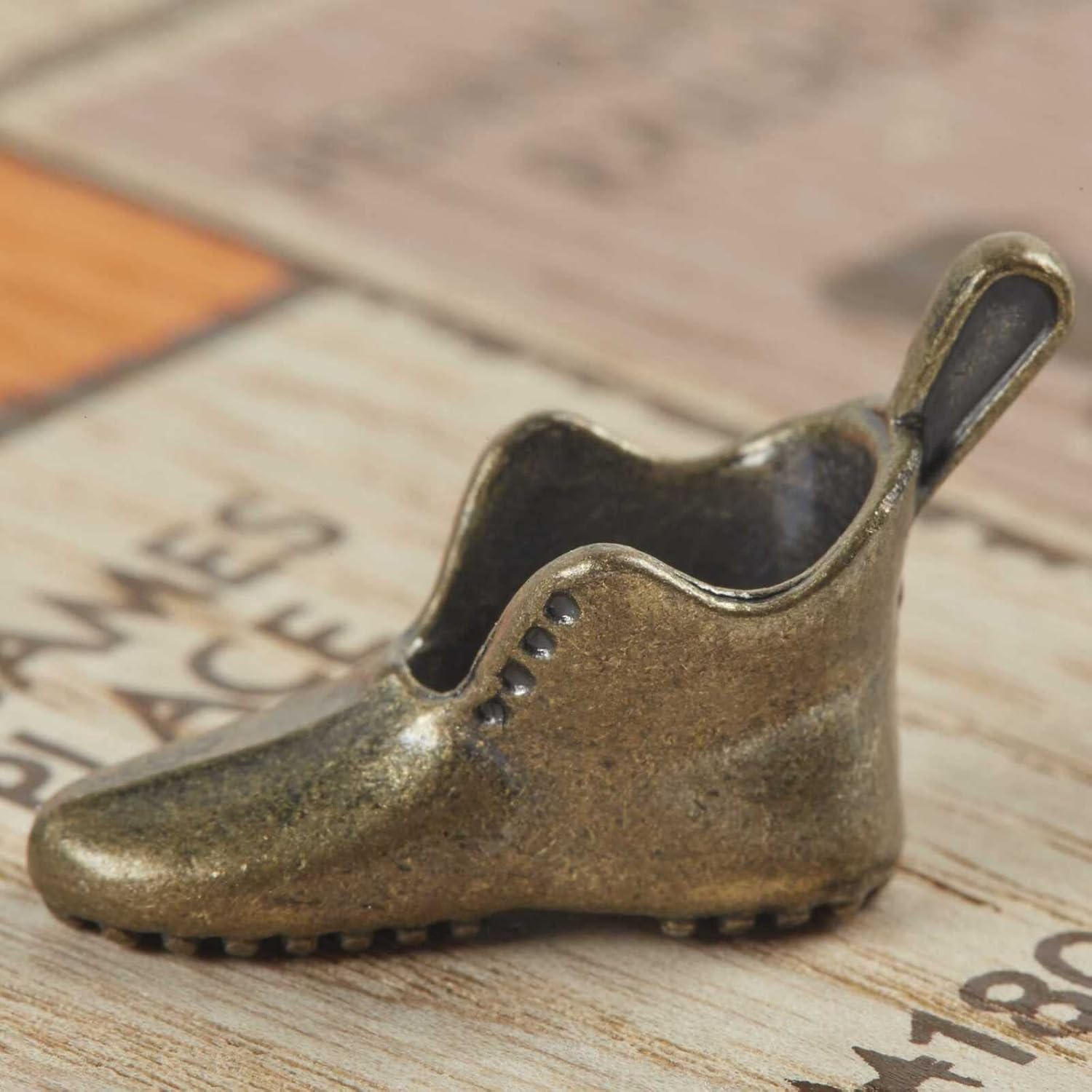 Ein kleiner bronzefarbener Schuh auf einer Holzoberfläche.