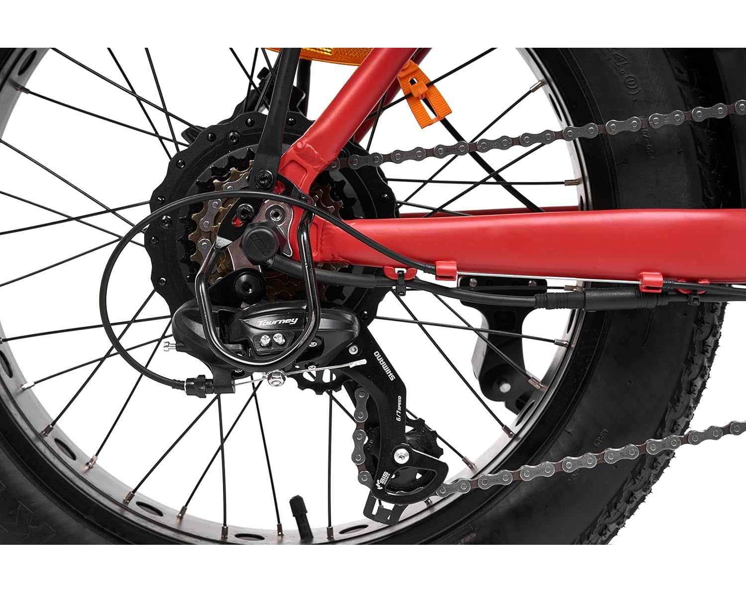 Primo piano di una ruota di bicicletta. Telaio rosso, ingranaggi neri e pneumatico spesso.
