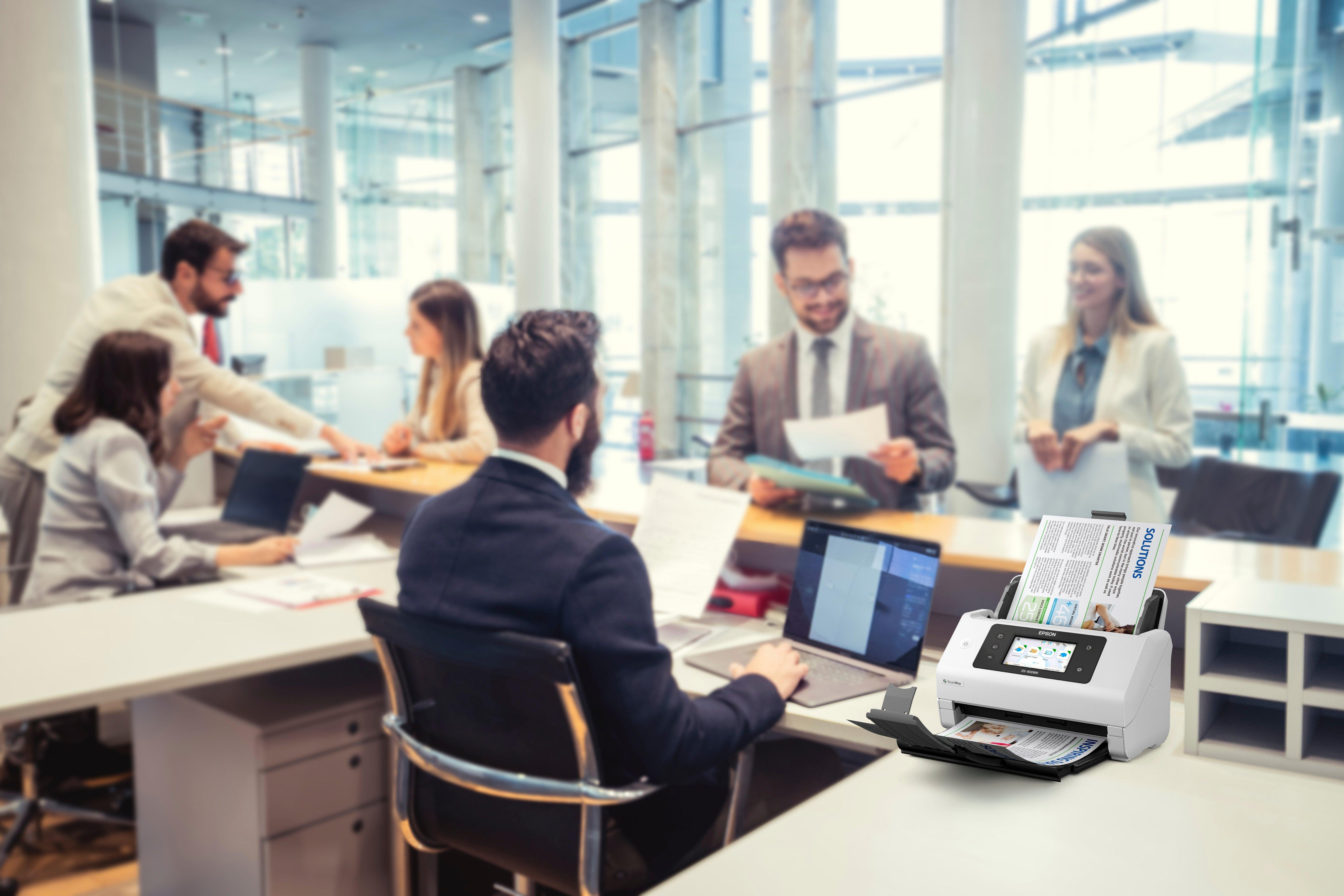 Scena biurowa z używanym skanerem, ludzie pracujący w tle.