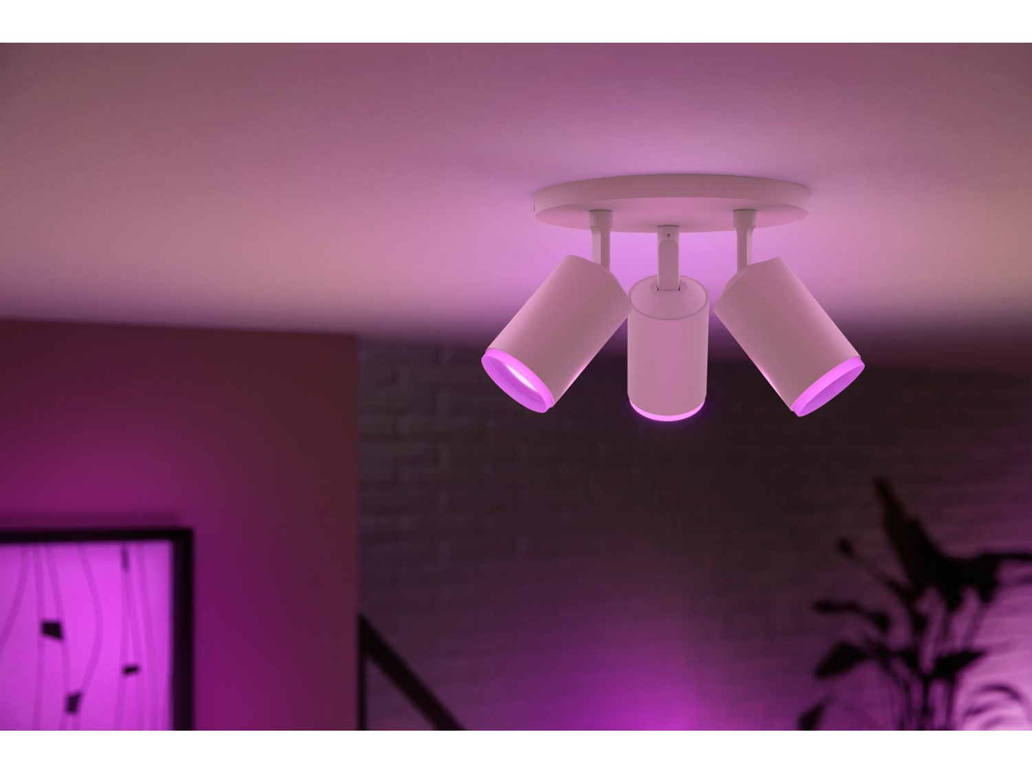 Drie witte spots aan een plafond, die elk roze licht uitstralen.
