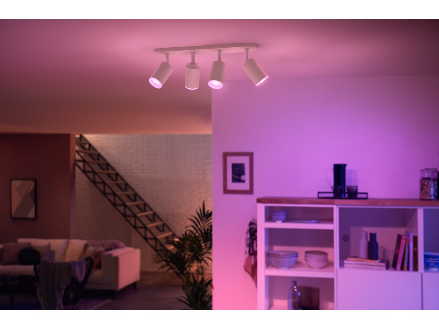 Quatre spots blancs sur un plafond blanc, éclairant une pièce avec un éclairage violet.
