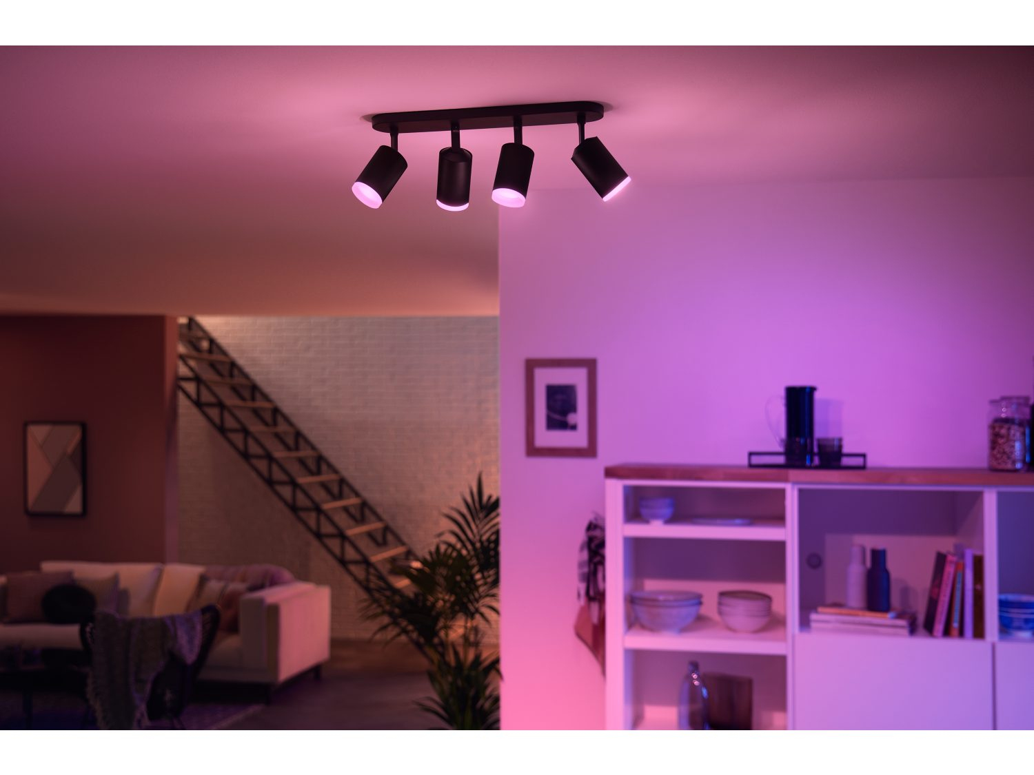 Een plafond met spots. De kamer is roze. Er is een trap en een kast.