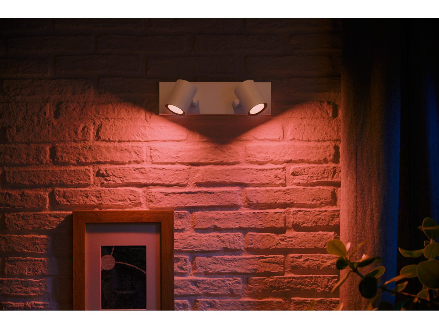 Dwa białe reflektory na ceglanej ścianie, rzucające czerwone światło z ramką poniżej.